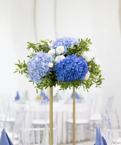 Ikebana sa plavo-belim cvećem kao dekoracija za sto, postavljena na zlatnom stalku
