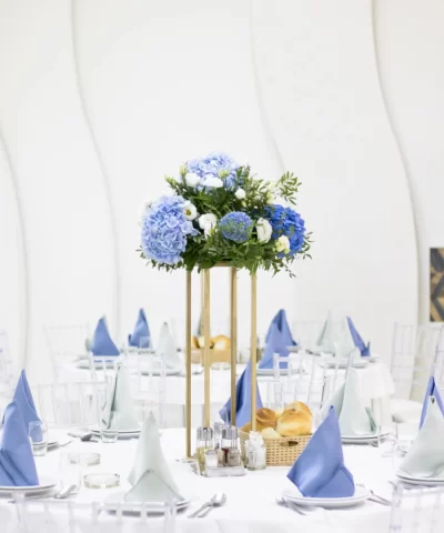 Ikebana sa plavo-belim cvećem kao dekoracija za sto, postavljena na zlatnom stalku